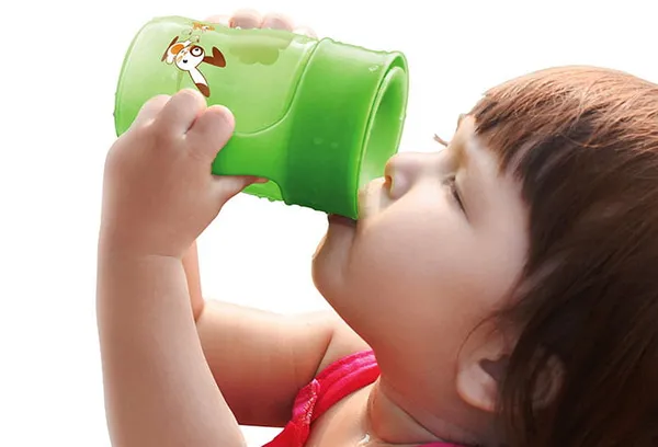 Ребенок пьет из детской кружки