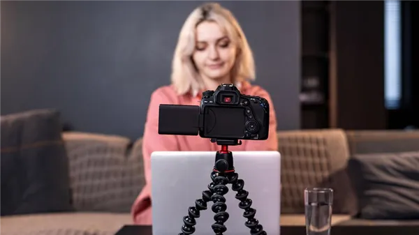 Девушка записывает видео на камеру, установленную на штативе на столе